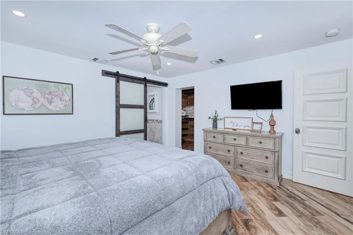 Master Bedroom featuring a spacious cedar lined closet, a closet, a barn doorwood plank tile  into the bath, flooring, and ceiling fan