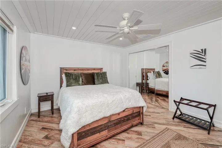 Bedroom with  wood plank tile flooring, ceiling fan, wood ceiling, a closet, and ornamental molding