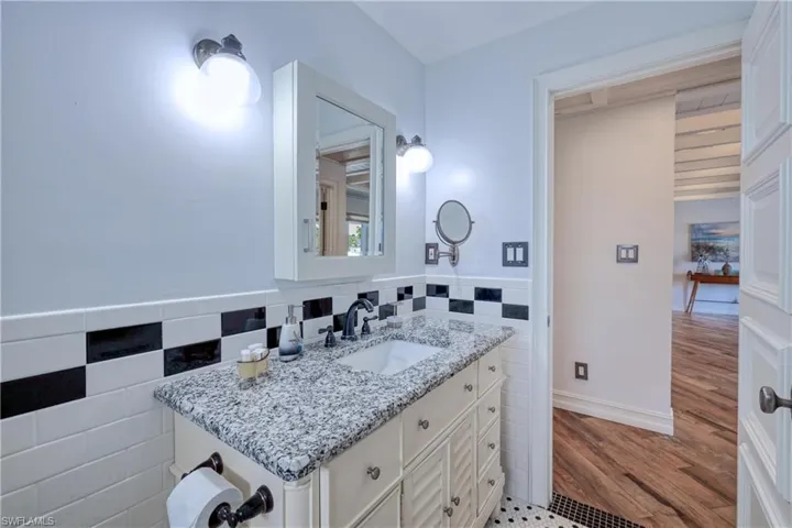 Bathroom featuring vanity, tile walls, tasteful backsplash, and tile floors