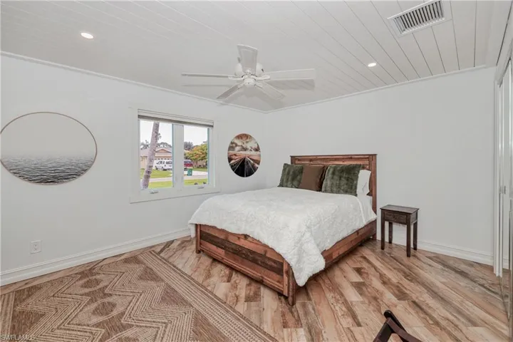 Bedroom featuring wood plank tile flooring, crown molding, and ceiling fan