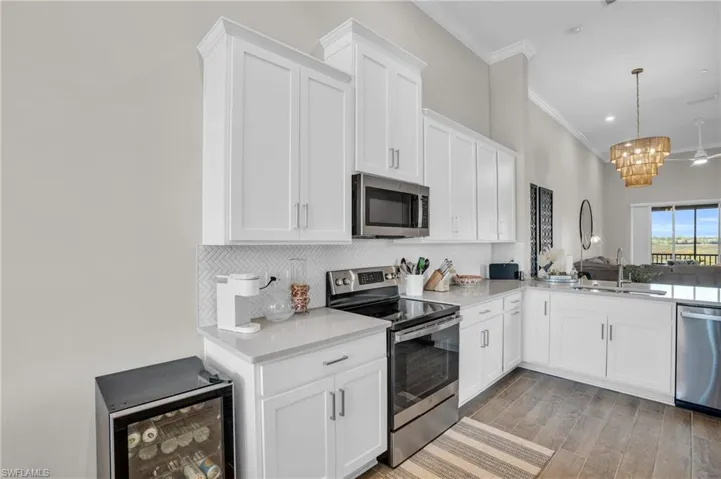 Kitchen featuring tasteful backsplash, ornamental molding, a sink, stainless steel appliances, and wine cooler