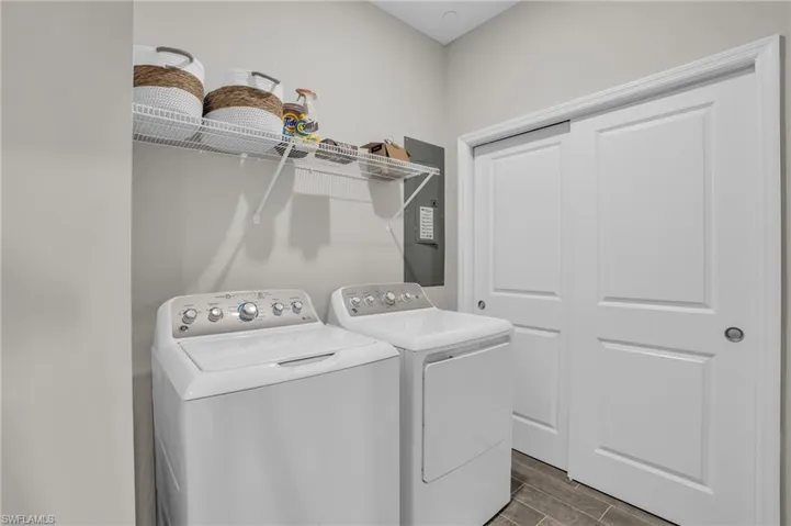 Clothes washing area featuring washer and dryer, laundry area, and wood finish floors
