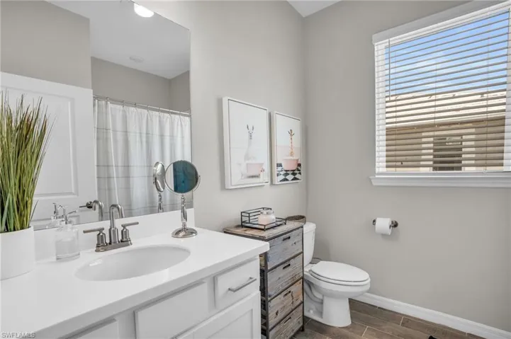 Full bath featuring toilet, vanity, baseboards, and a healthy amount of sunlight