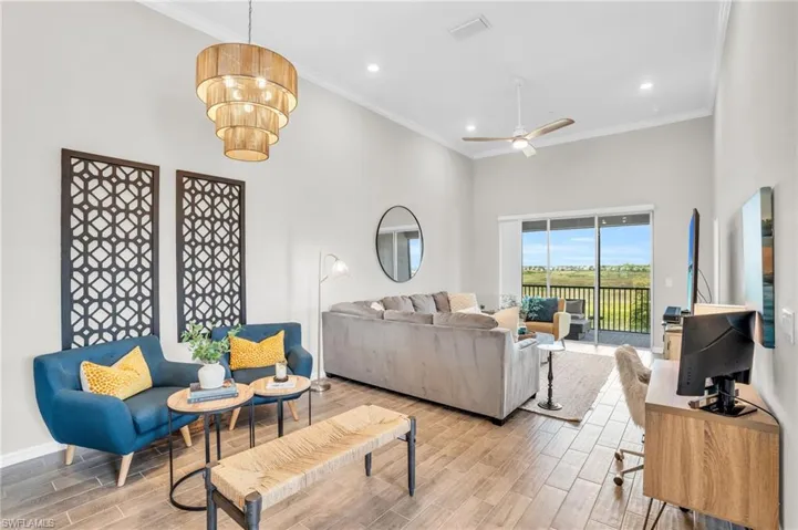 Living room featuring crown molding, a high ceiling, light wood finished floors, and ceiling fan