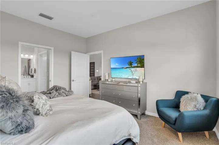 Bedroom with carpet, visible vents, baseboards, and connected bathroom