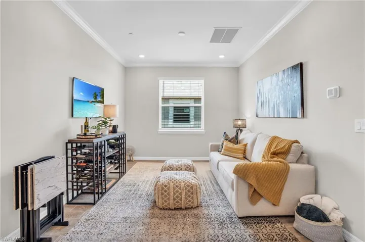 Living room with crown molding, baseboards, and visible vents