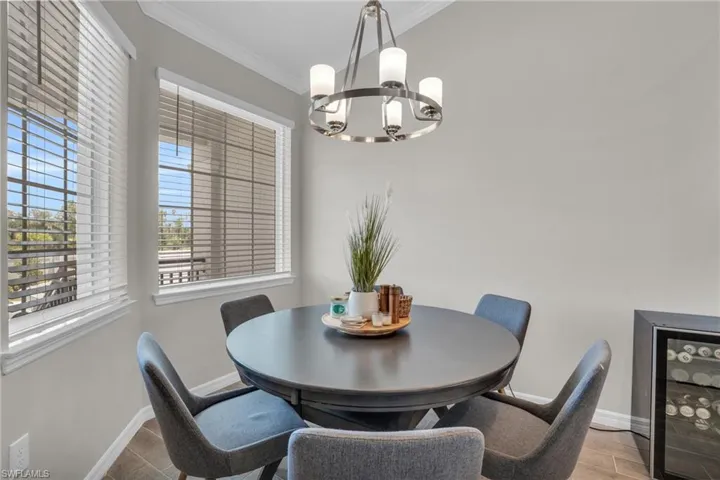 Dining area featuring crown molding, a notable chandelier, wine cooler, and baseboards