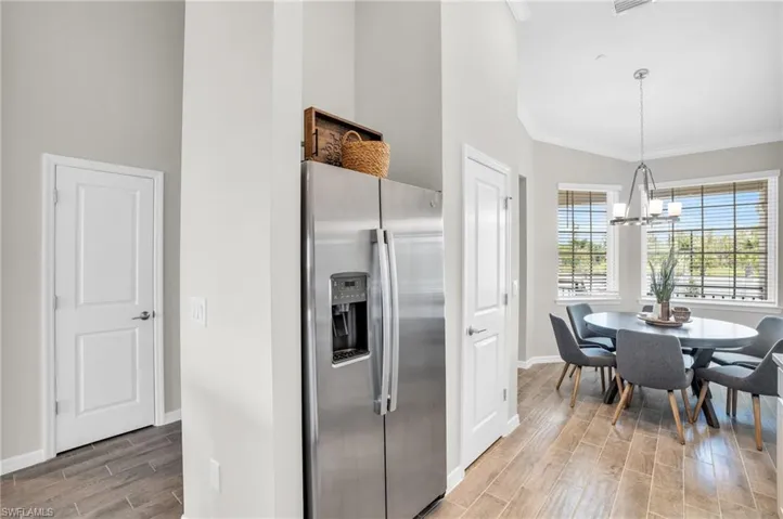 Kitchen featuring baseboards, ornamental molding, a chandelier, stainless steel refrigerator with ice dispenser, and light wood-style floors