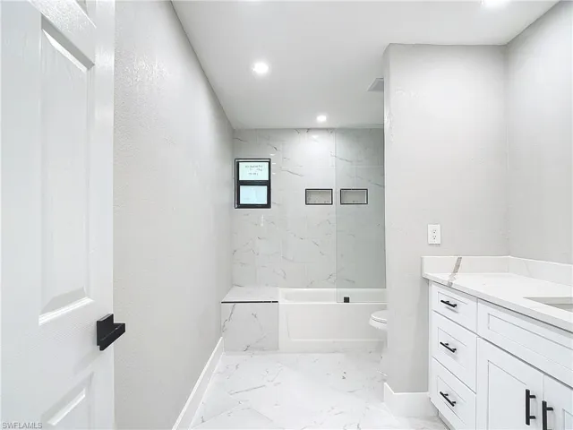 Full bathroom with tiled shower / bath, vanity, toilet, and tile floors
