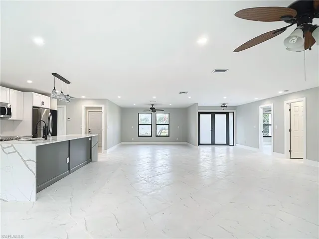 Unfurnished living room featuring sink, ceiling fan, and light tile floors