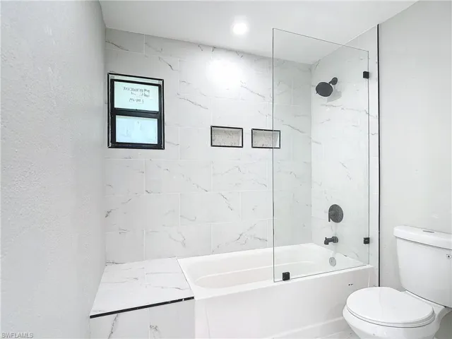 Bathroom with tiled shower / bath and toilet
