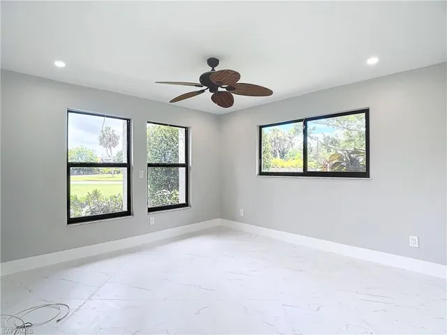 Empty room with ceiling fan and light tile flooring