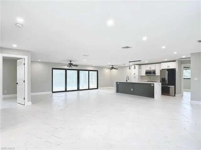 Unfurnished living room with sink, light tile flooring, and ceiling fan