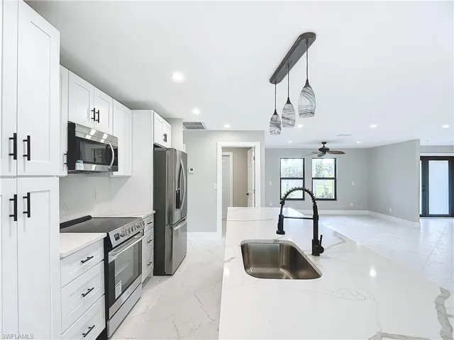 Kitchen with appliances with stainless steel finishes, white cabinetry, sink, and pendant lighting