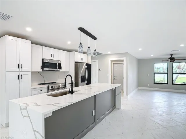 Kitchen featuring decorative light fixtures, appliances with stainless steel finishes, ceiling fan, and white cabinets