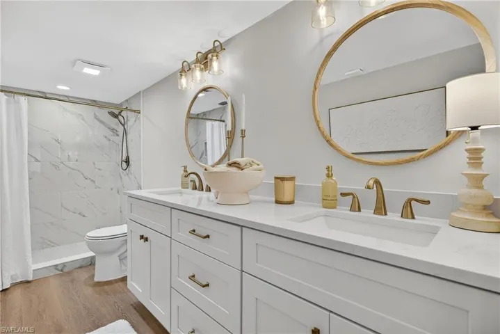 Bathroom with double vanity, a shower stall, and light wood-style flooring