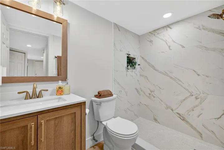 Full bathroom with vanity, a marble finish shower, and recessed lighting