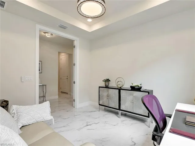 Office area featuring light marble finish floors, recessed lighting, and a raised ceiling