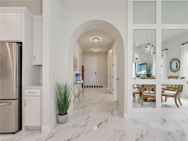 Hallway featuring arched walkways, light marble finish flooring, and recessed lighting