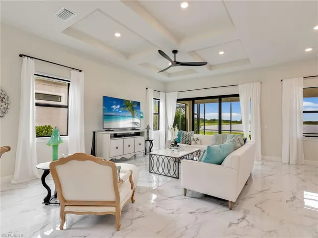 Living area with coffered ceiling, ceiling fan, recessed lighting, beam ceiling, and light marble finish flooring