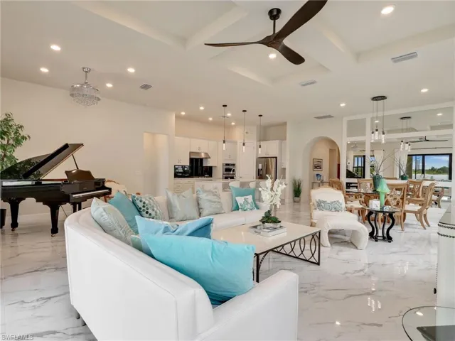 Living area featuring recessed lighting, coffered ceiling, arched walkways, light marble finish floors, and a ceiling fan