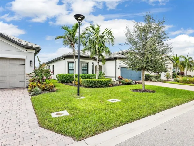 Single story home featuring stucco siding, driveway, a front yard, and a tile roof