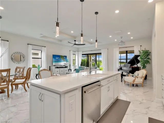 Kitchen with light stone countertops, light marble finish flooring, dishwasher, open floor plan, and white cabinets