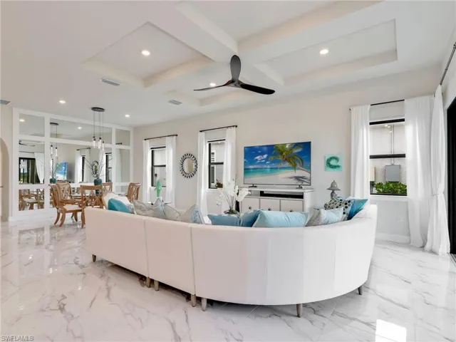 Living area with coffered ceiling, ceiling fan, recessed lighting, light marble finish floors, and beam ceiling