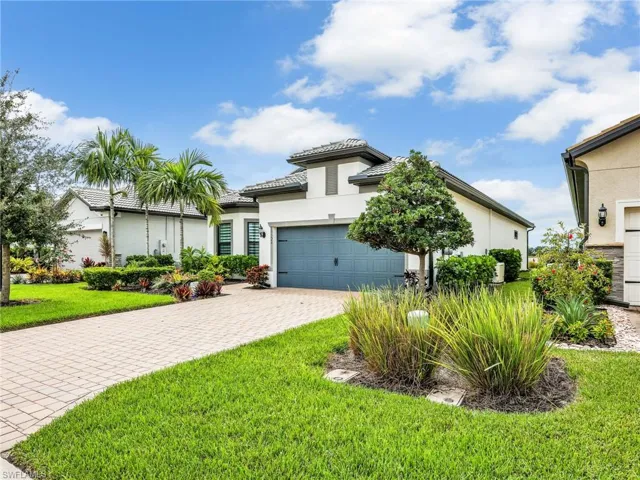 View of front facade featuring stucco siding, decorative driveway, a front yard, and a garage