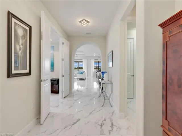 Corridor featuring arched walkways and light marble finish floors