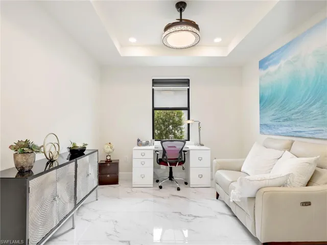 Office space with light marble finish flooring, recessed lighting, and a tray ceiling