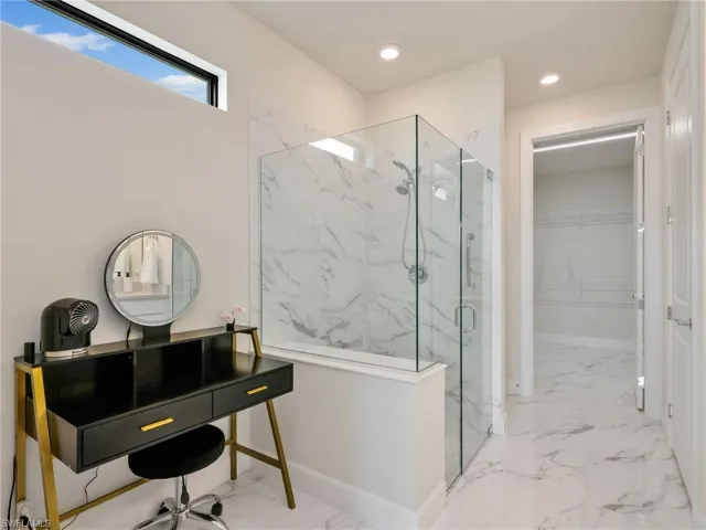 Full bath with marble tiled flooring, plenty of natural light, a marble finish shower, a walk in closet, and recessed lighting
