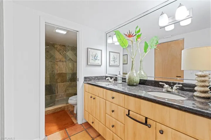Bathroom featuring double vanity, a stall shower, and light tile patterned floors