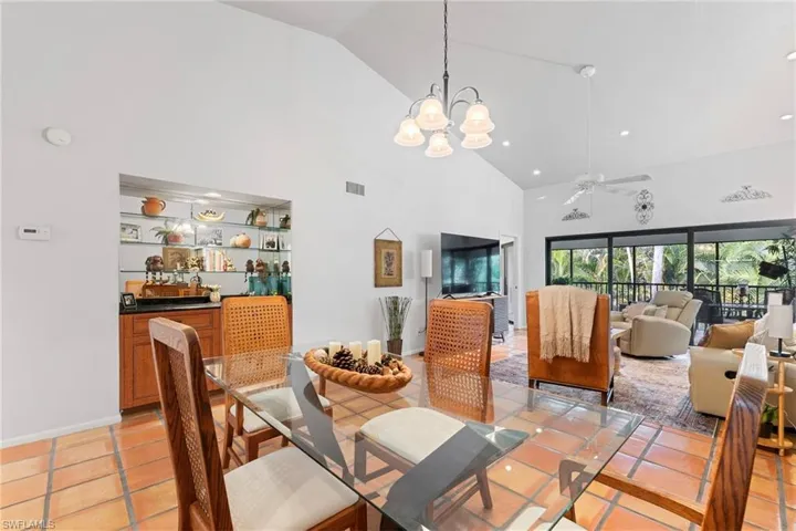 Dining area with a ceiling fan, high vaulted ceiling, a chandelier, and light tile patterned flooring