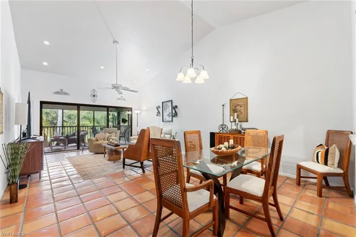 Dining space featuring high vaulted ceiling, a ceiling fan, light tile patterned floors, and a chandelier