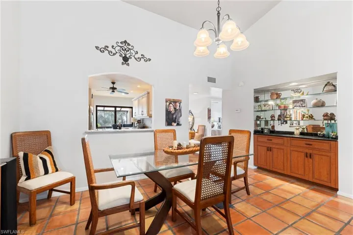 Dining room featuring a ceiling fan, a chandelier, arched walkways, and high vaulted ceiling