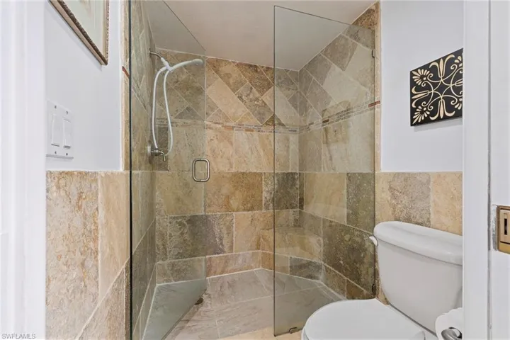 Bathroom featuring a shower stall and tile walls