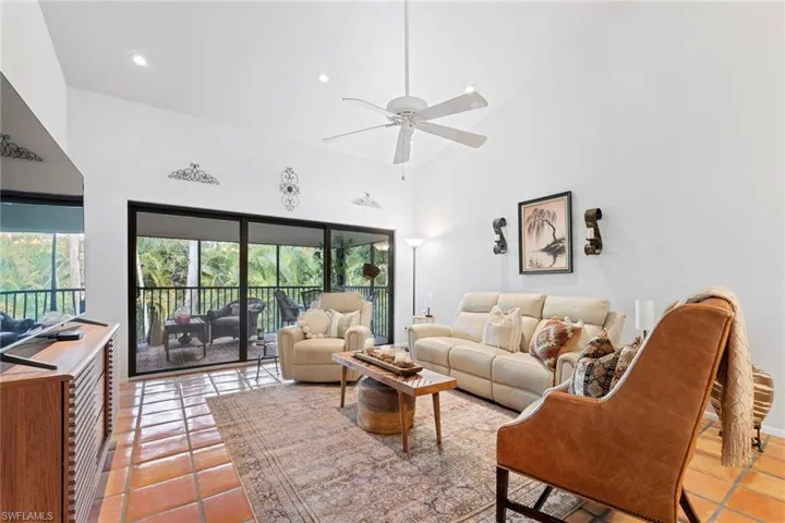 Living room featuring high vaulted ceiling, ceiling fan, and light tile patterned floors