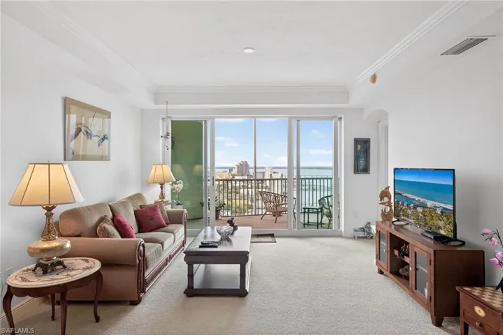 Living area with light carpet, crown molding, and arched walkways