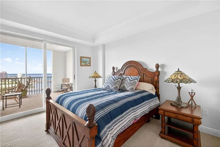 Bedroom with light colored carpet, access to outside, crown molding, a water view, and floor to ceiling windows