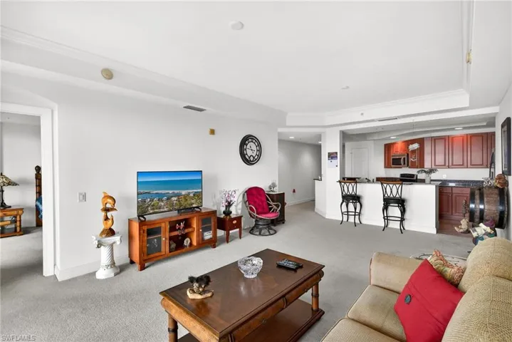 Living room with ornamental molding, light carpet, recessed lighting, and a raised ceiling