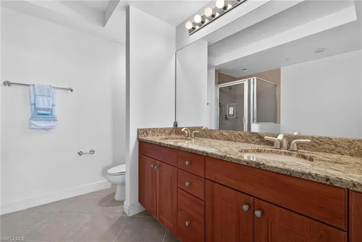 Bathroom featuring double vanity, a shower stall, and light tile patterned floors