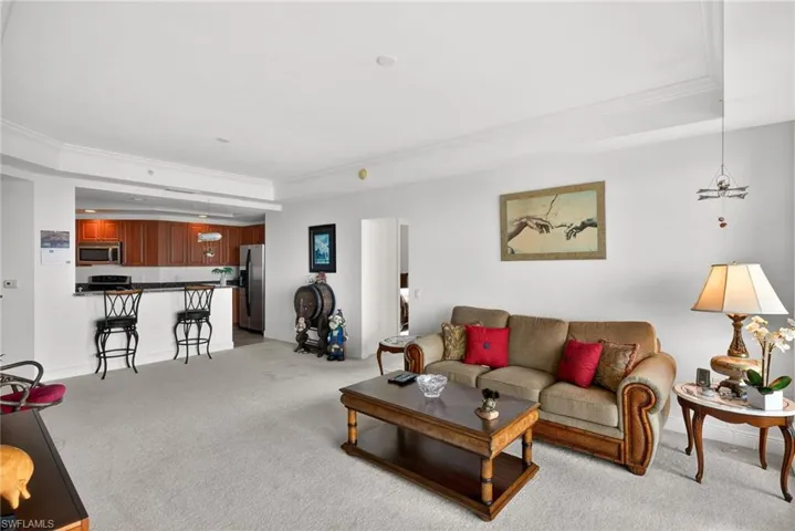 Living area featuring a tray ceiling, light carpet, and ornamental molding