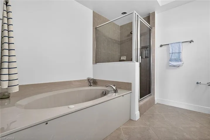 Full bathroom featuring a shower stall, light tile patterned flooring, and a bath