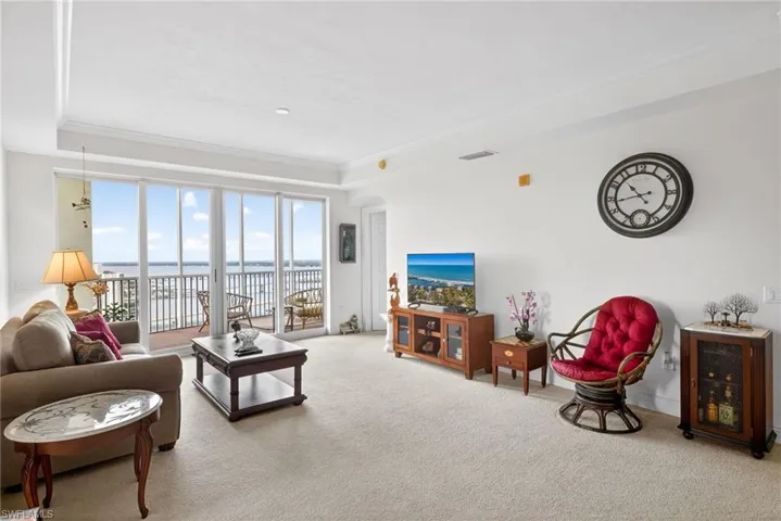Living area featuring ornamental molding, light carpet, and arched walkways