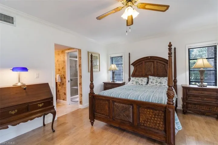Primary Bedroom with ensuite bathroom, ceiling fan, Tile wood-like flooring, and ornamental molding