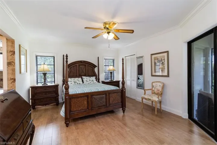 Primary Bedroom featuring two walk-in closet, wood-like flooring, ornamental molding, and ceiling fan