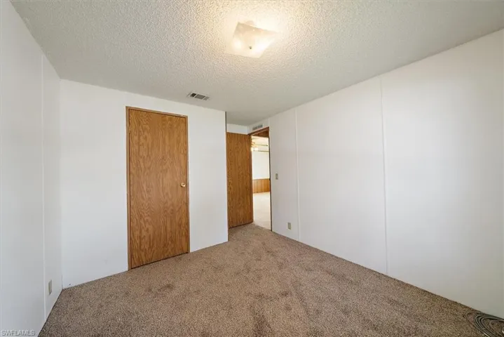 Unfurnished bedroom with a textured ceiling, carpet floors, and a closet