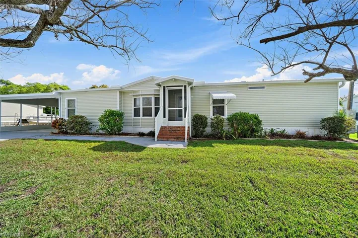 Manufactured / mobile home with an attached carport, a front yard, and entry steps