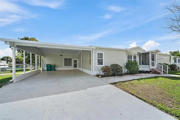View of front of house with a carport, concrete driveway, a front lawn, and a sunroom